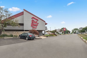 A Red Roof Inn with a modern design, a parking lot, and a clear sky. - Red Roof Inn Lansing East – MSU (Lansing)