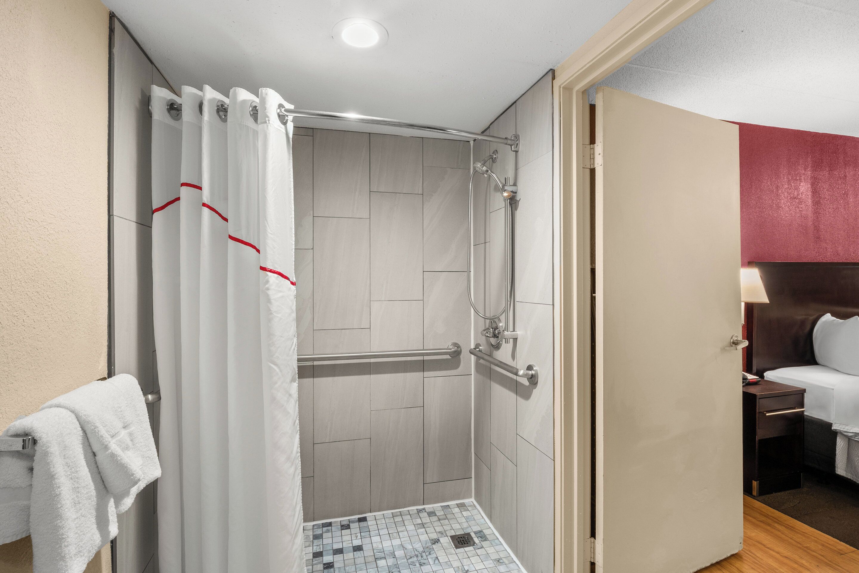 A hotel bathroom with a shower, a toilet, and a sink.