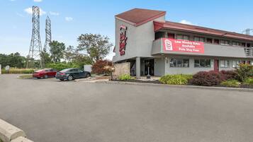 A Red Roof Inn with a sign advertising low weekly rates and a parking lot with several cars.