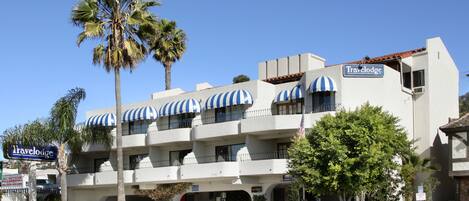 Un hotel Travelodge con fachada blanca, varios balcones y toldos a rayas.