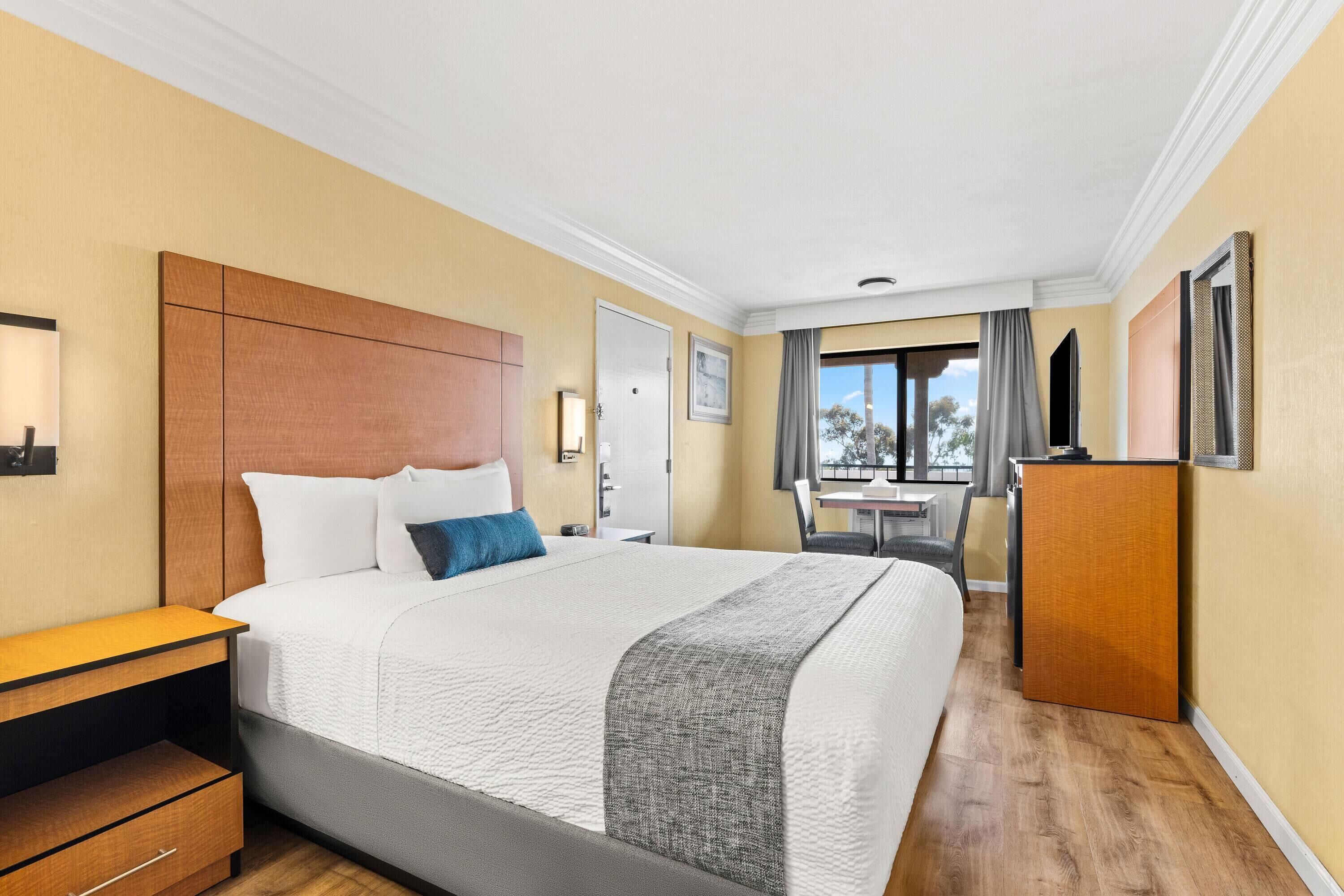 Une chambre d’hôtel avec un grand lit, un bureau, une armoire et une vue sur l’extérieur.