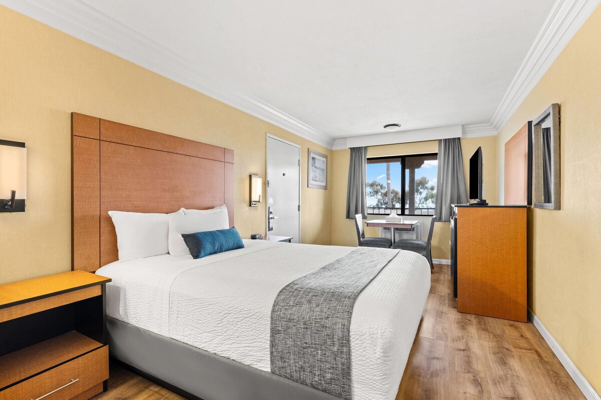 Hotellihuone, jossa on suuri sänky, työpöytä, vaatekaappi ja näkymä ulos.