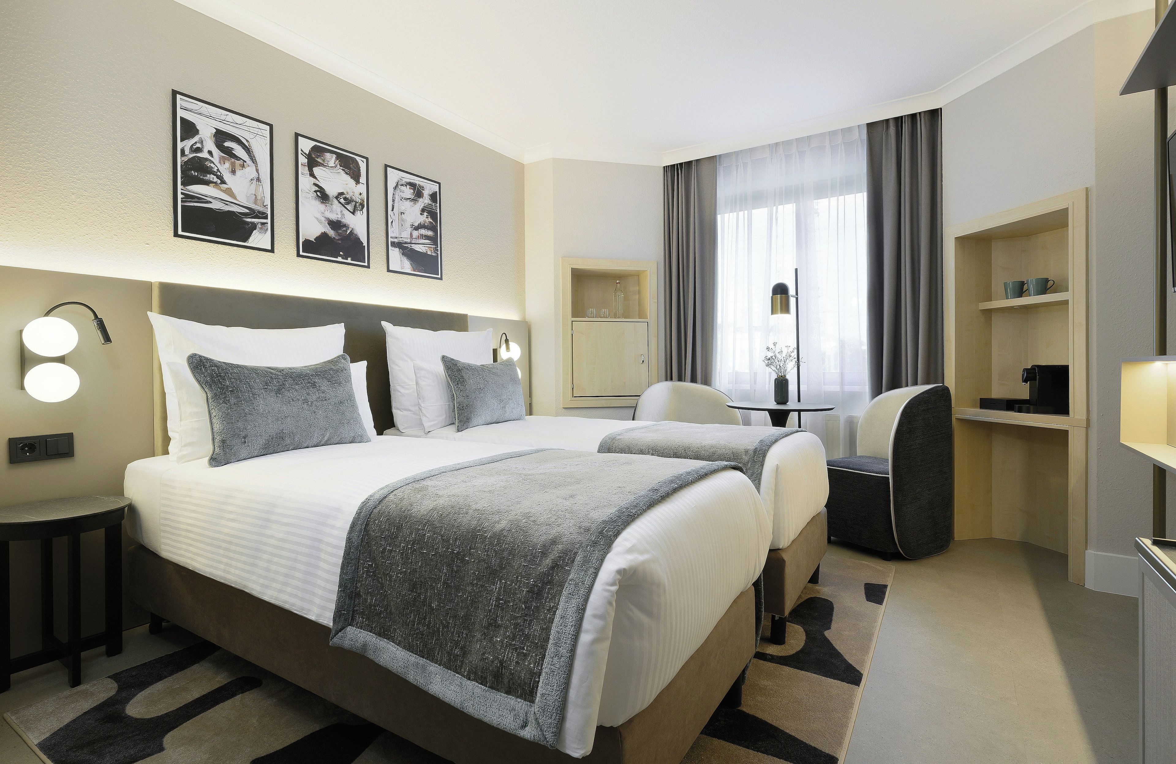 Ein Hotelzimmer mit einem großen Bett, zwei Nachttischen, einem Schreibtisch, einem Stuhl und einem Kleiderschrank.