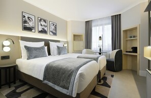 A hotel room with a large bed, two bedside tables, a desk, a chair, and a wardrobe.