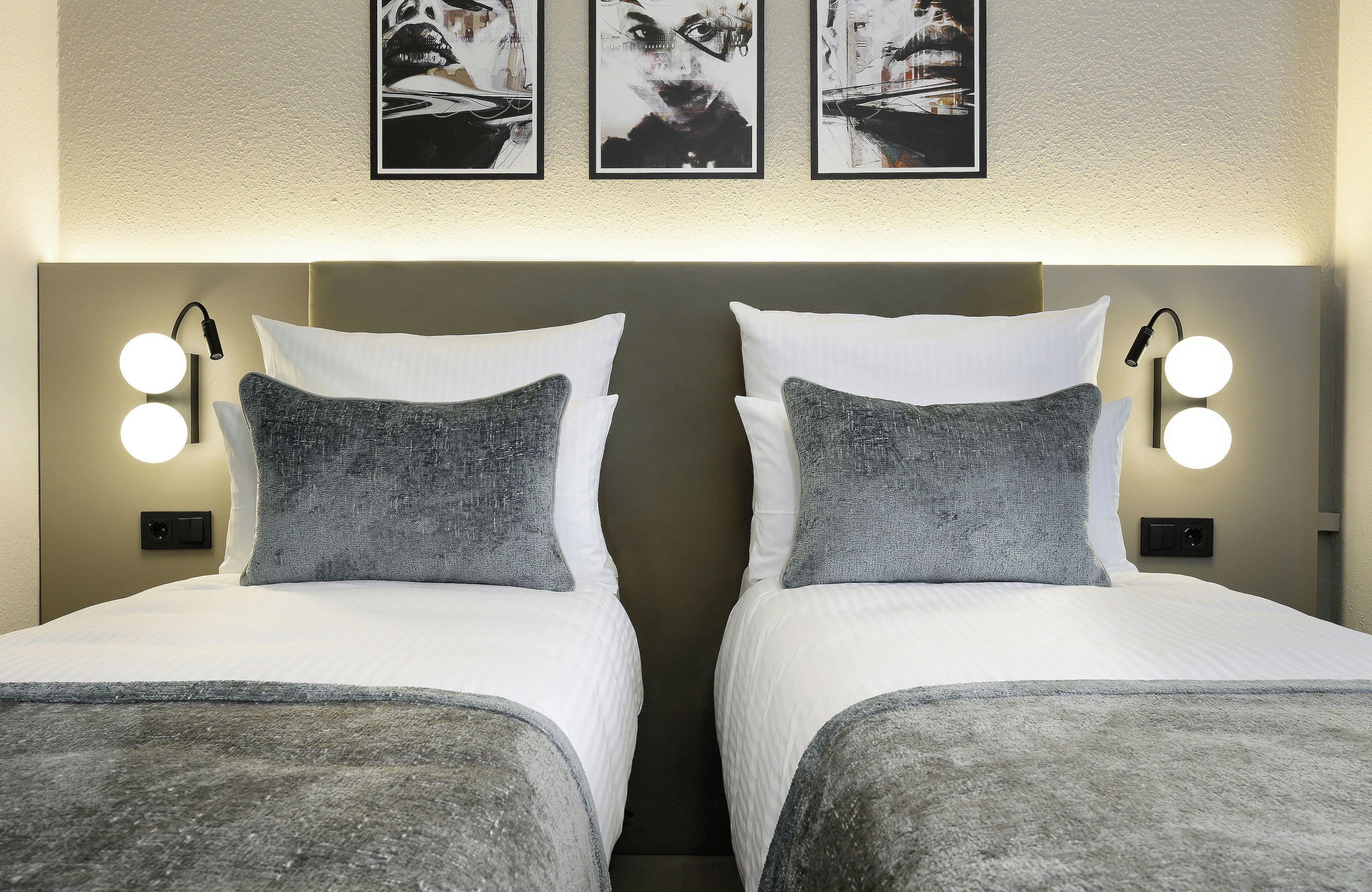 A double bed with two pillows and a headboard with wall-mounted lights.