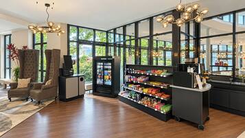 Un espacio comercial moderno con zona de estar, dispensador de bebidas y estantes llenos de aperitivos.