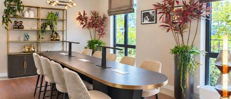 Un comedor moderno con una mesa larga, sillas y diversas plantas.