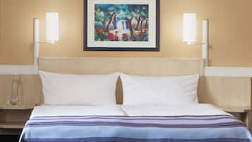 Ein Hotelzimmer mit einem Bett, zwei Nachttischen, einem gerahmten Gemälde und zwei Wandlampen.