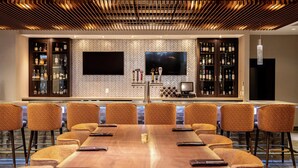 A conference room with a long table, six chairs, and a bar area with shelves of bottles.