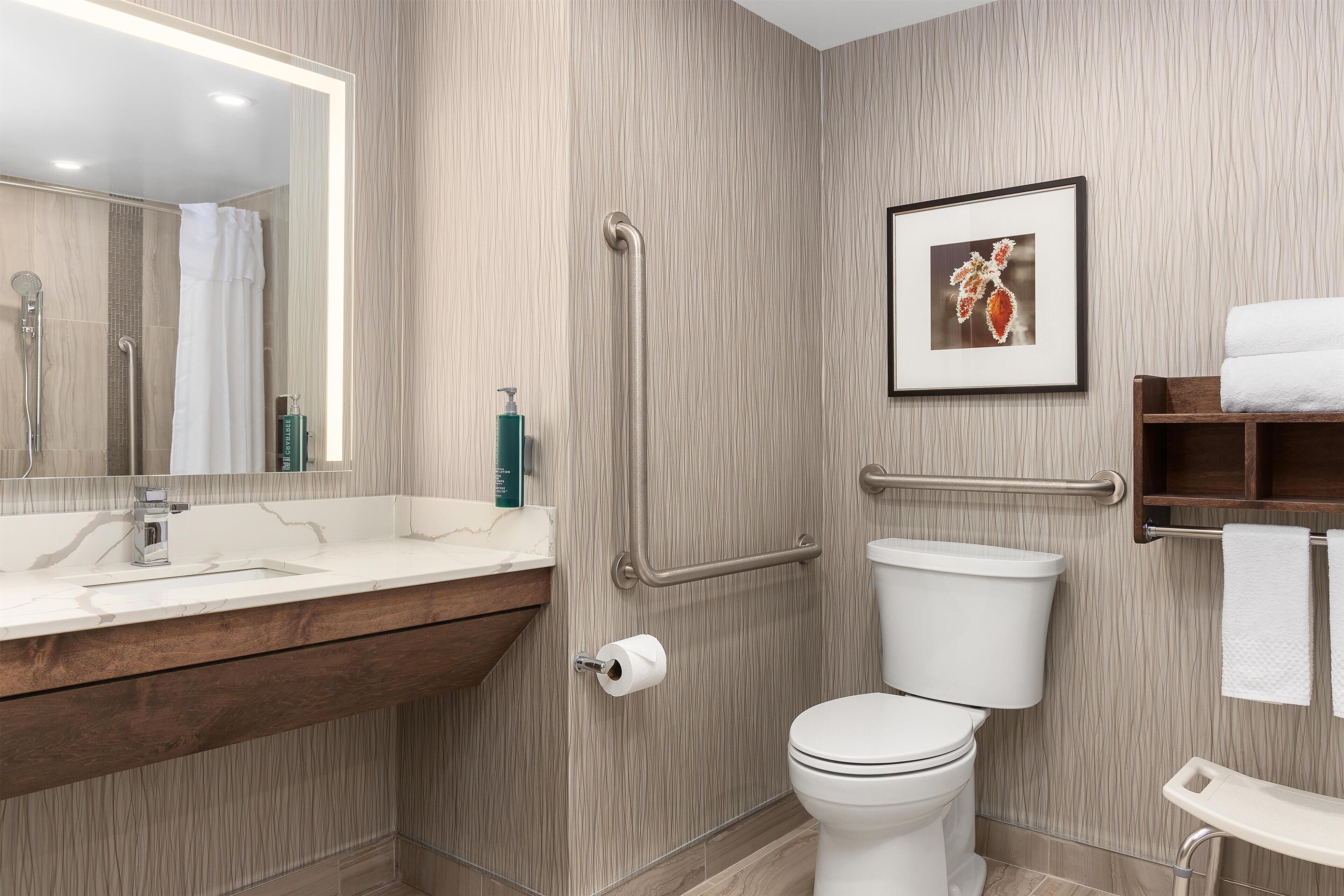 Un baño moderno con tocador de madera, inodoro y zona de ducha.