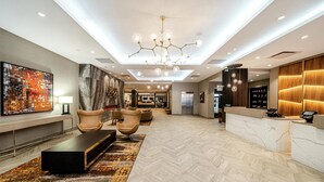 A modern lobby with a reception desk, seating area, and a large abstract painting.