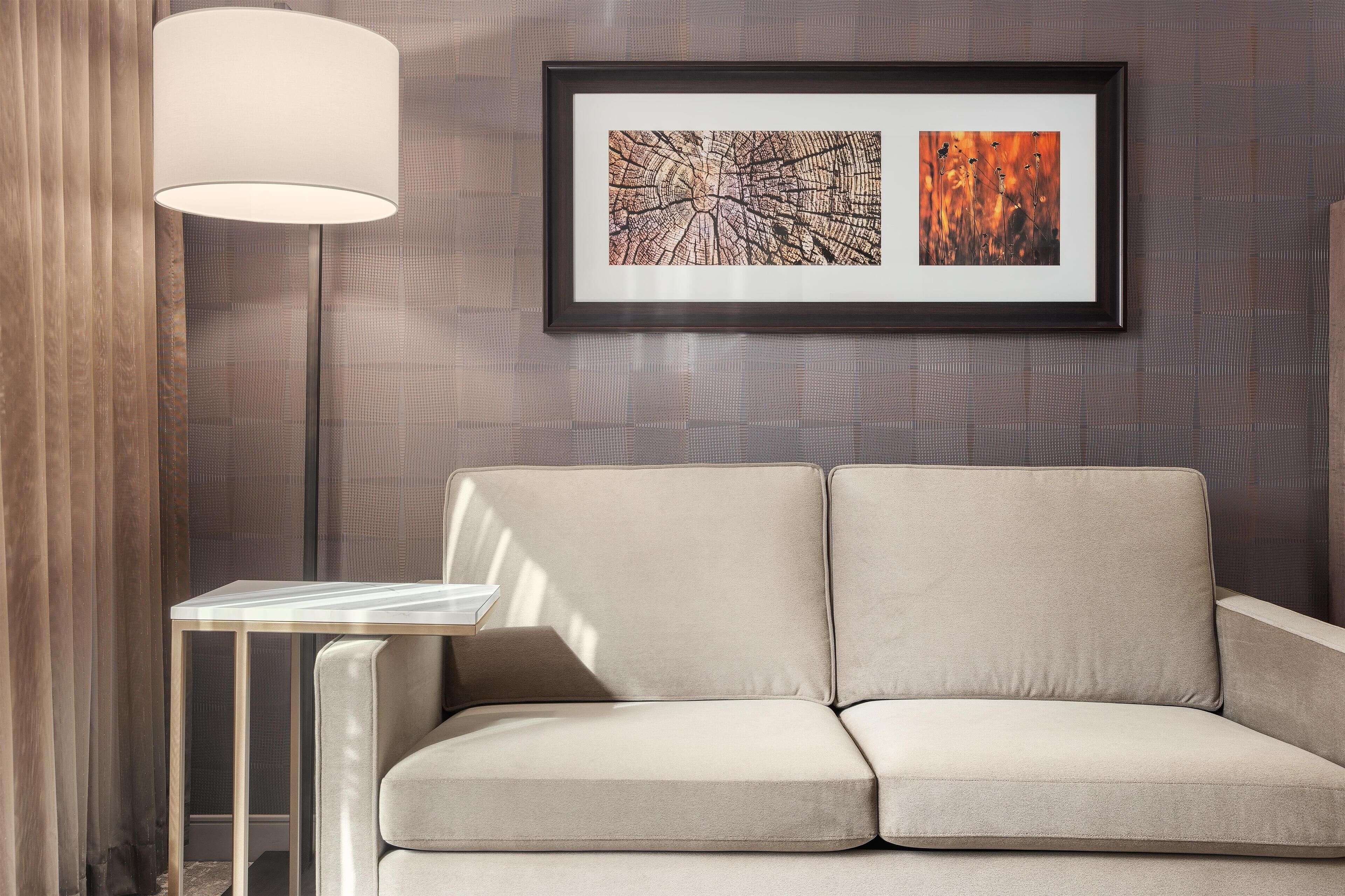 A modern living room with a sofa, a side table, and a framed abstract painting on the wall.