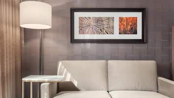 A modern living room with a sofa, a side table, and a framed abstract painting on the wall.