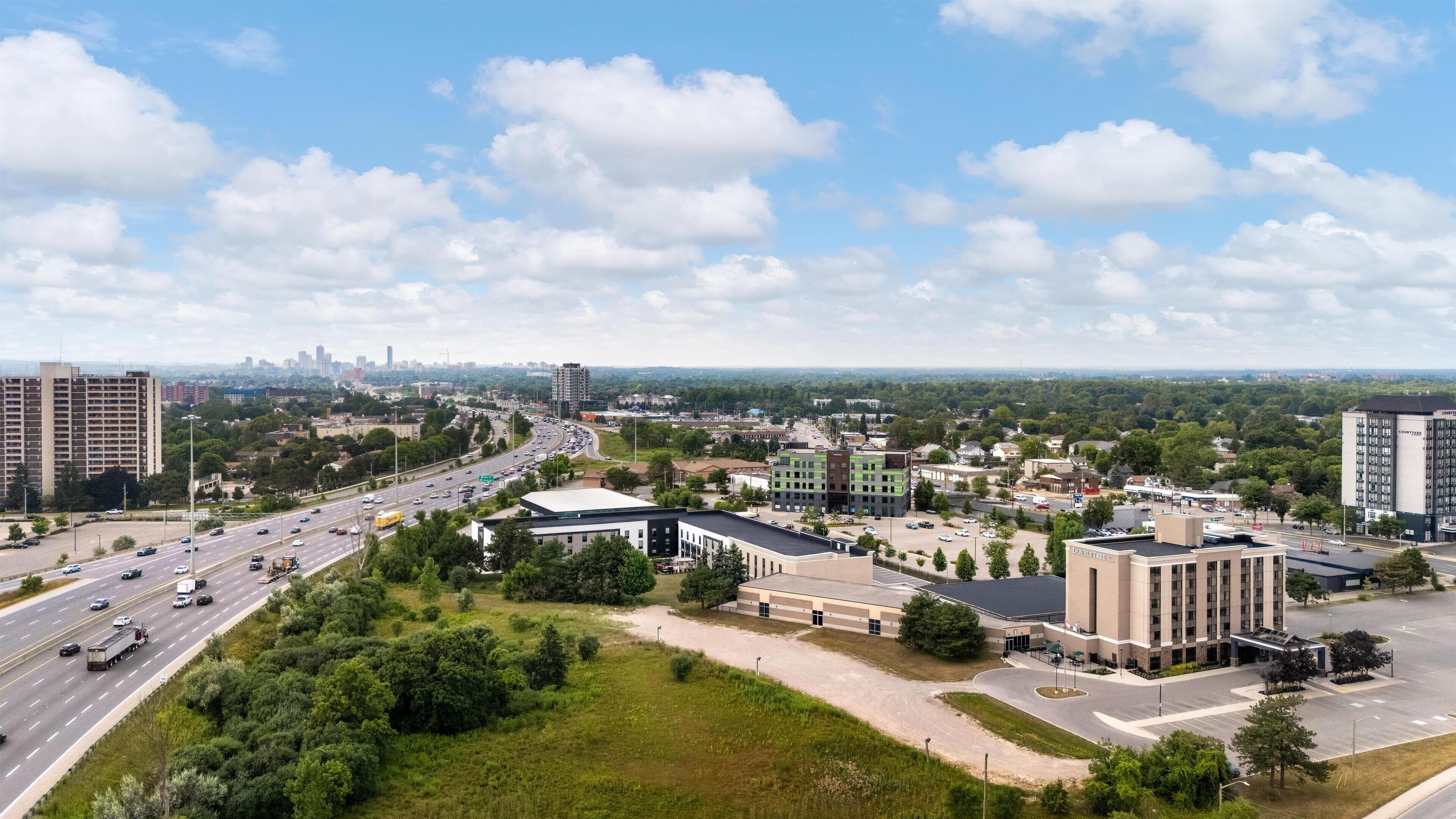 A cityscape with a highway, buildings, and greenery.