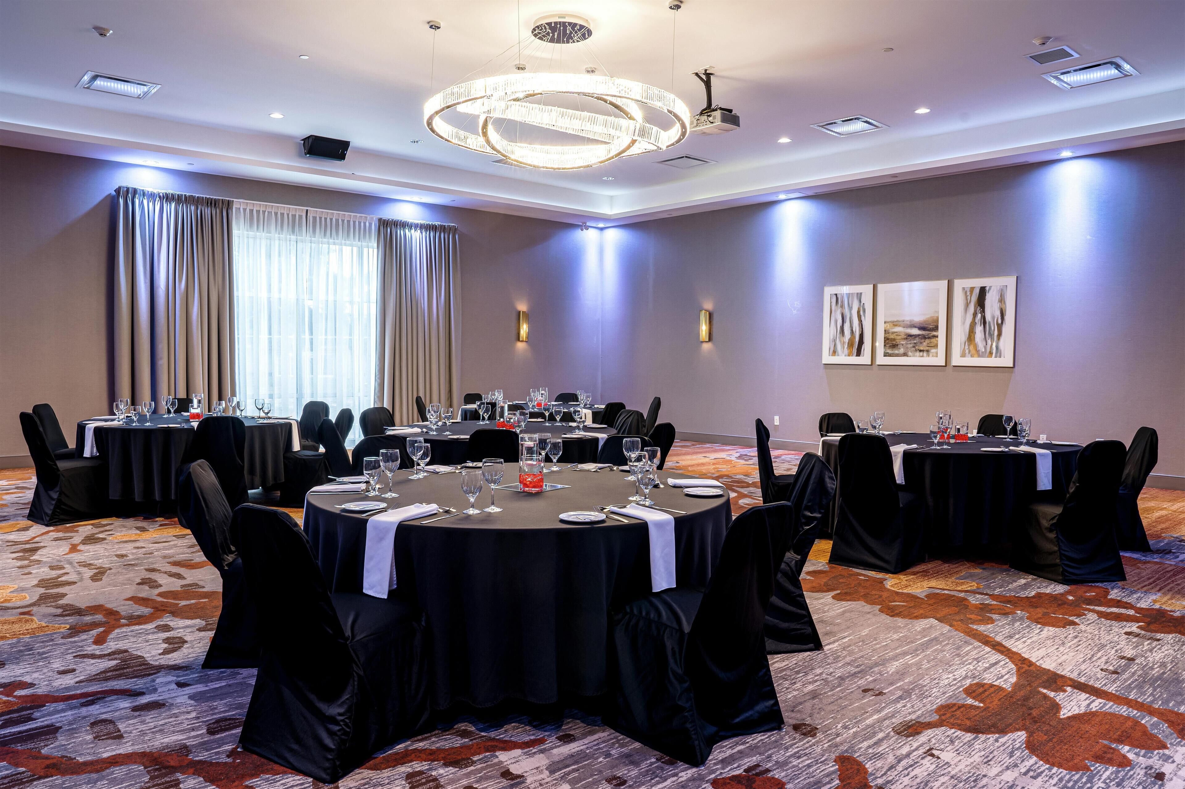 A conference room with round tables, black chairs, and a carpeted floor.