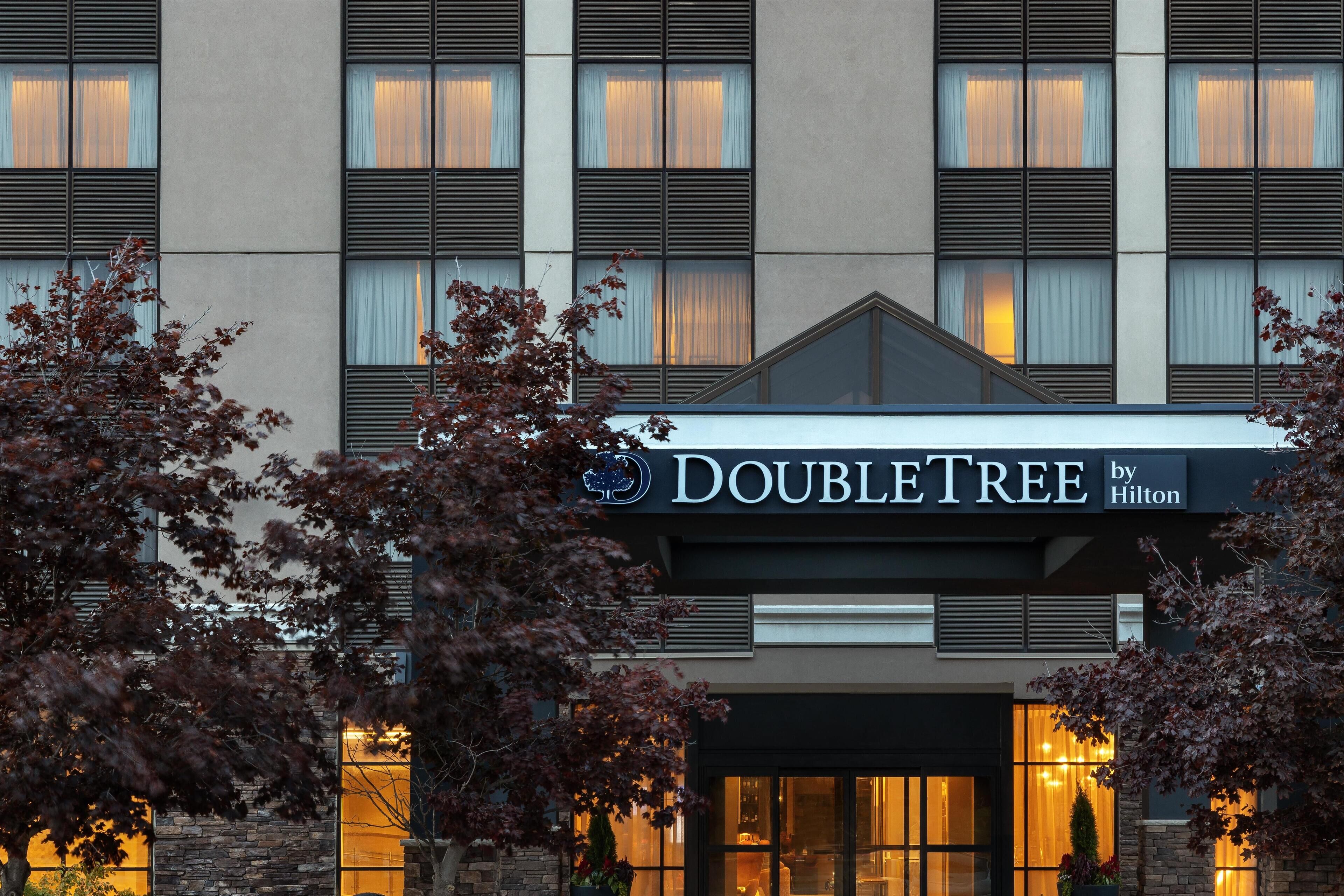A DoubleTree by Hilton hotel facade with a stone base, multiple windows, and a prominent sign.