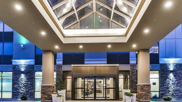A hotel entrance with a glass ceiling, stone pillars, and a modern facade.