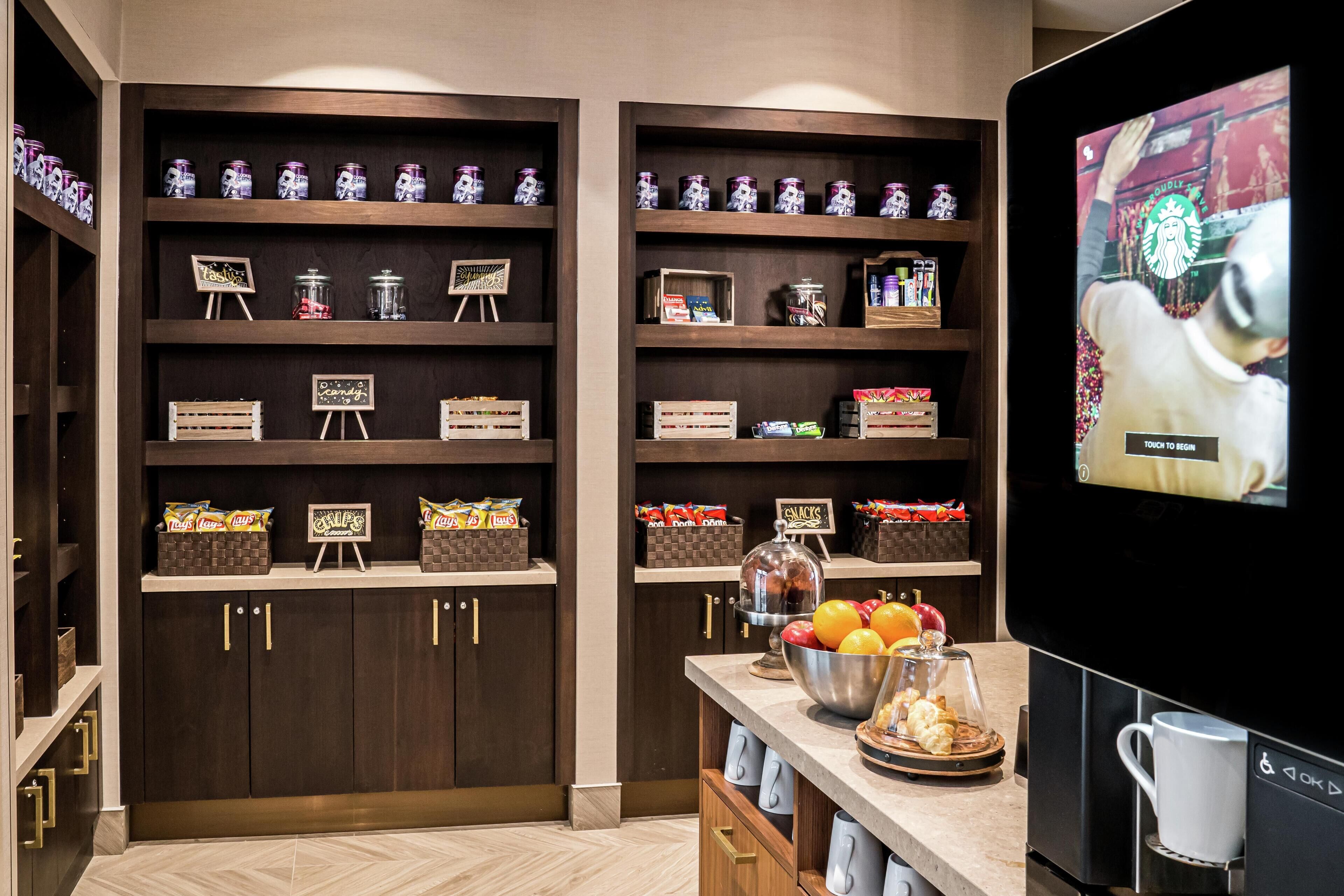 Una cocina moderna con armarios de madera, una cafetera y un televisor mostrando un anuncio de Starbucks.