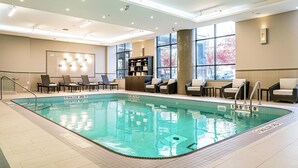 A hotel lobby with a swimming pool, seating area, and large windows.