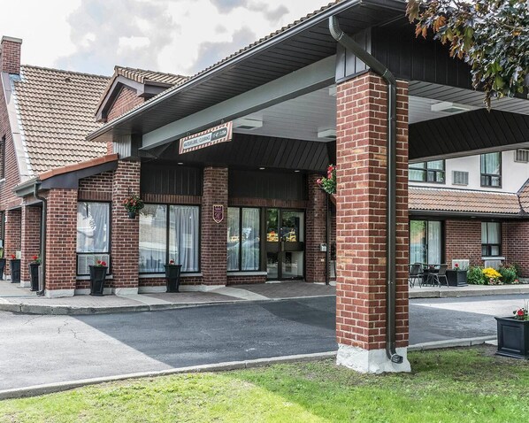 Un hôtel à la façade en briques, doté de grandes fenêtres et d’une entrée abritée.