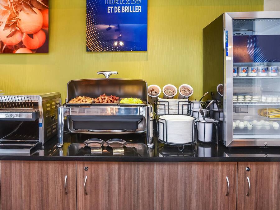 A breakfast bar with a toaster, a grill, and a refrigerator with yogurt containers.