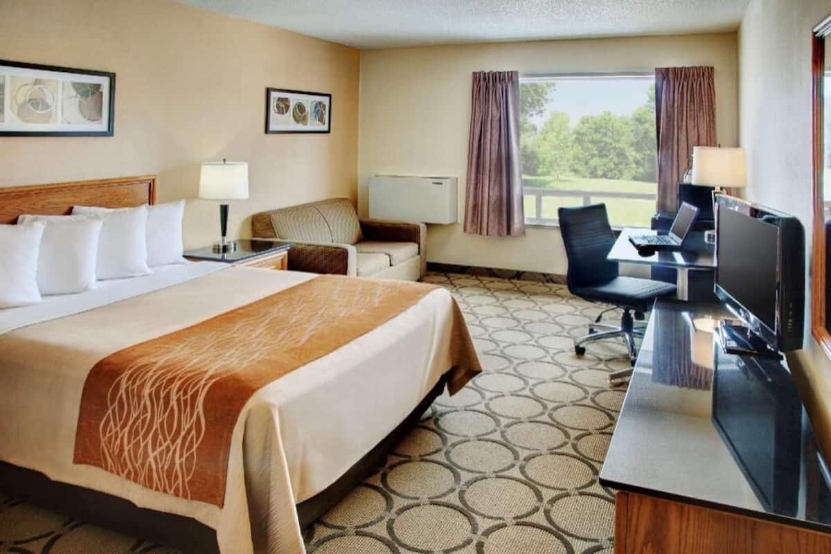 Une chambre d’hôtel équipée d’un lit, d’un bureau, d’une chaise, d’une télévision et d’une fenêtre avec des rideaux.
