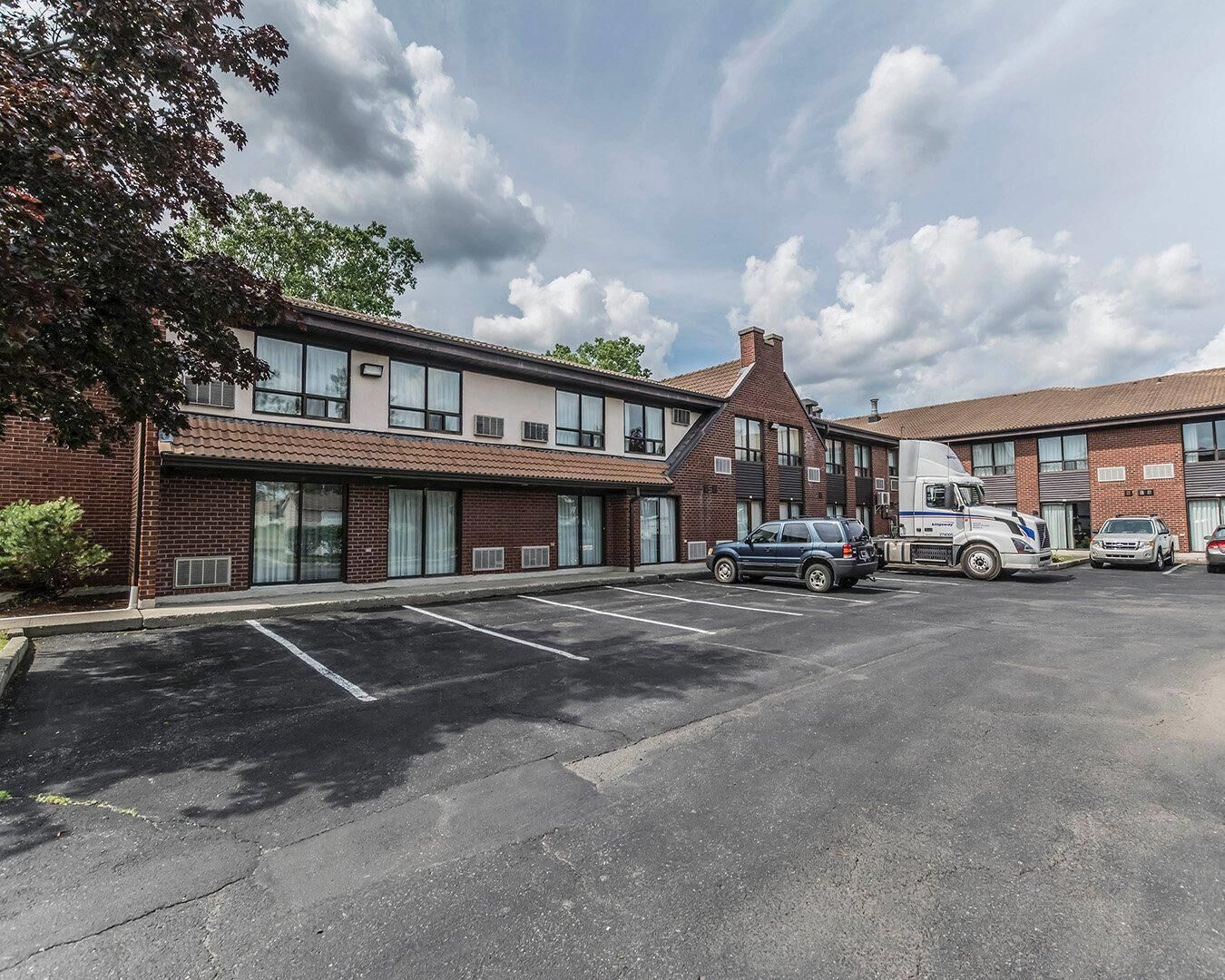 A two-story building with a parking lot, a truck, and a car.