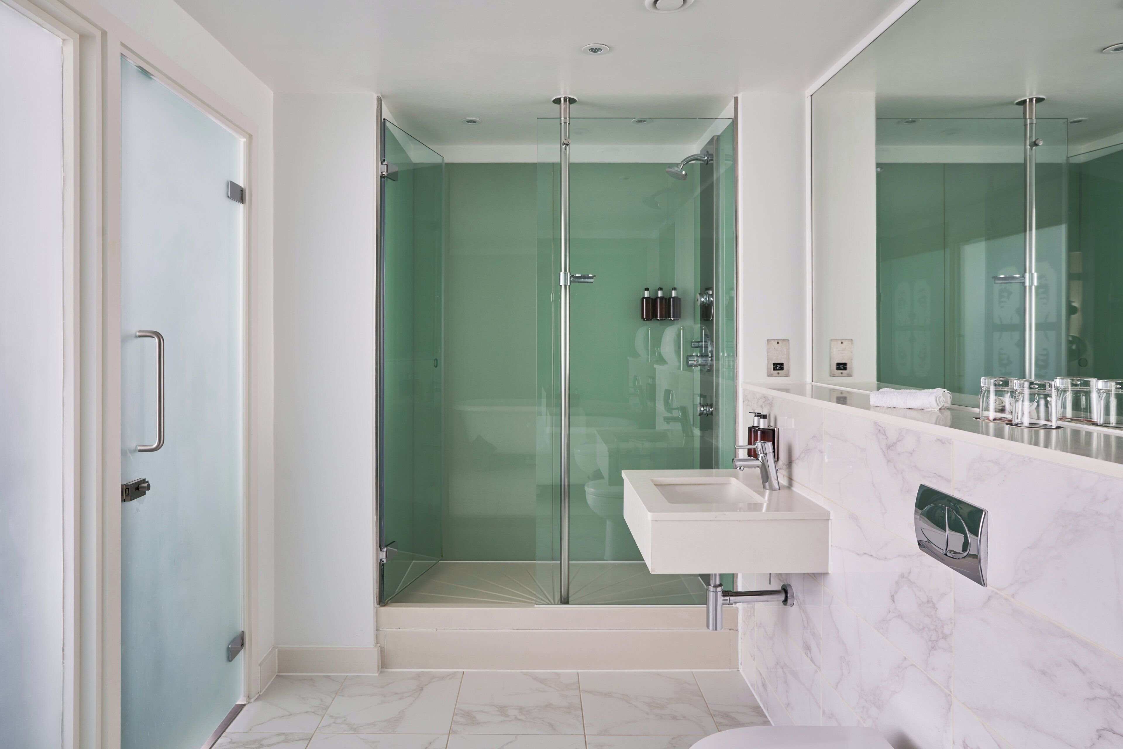 Ein modernes Badezimmer mit Duschkabine aus Glas, einem weißen Waschbecken und einem großen Spiegel.