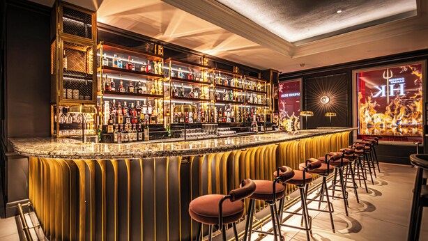 A bar with a curved counter, multiple shelves of bottles, and several stools. - The Cumberland, London (London)