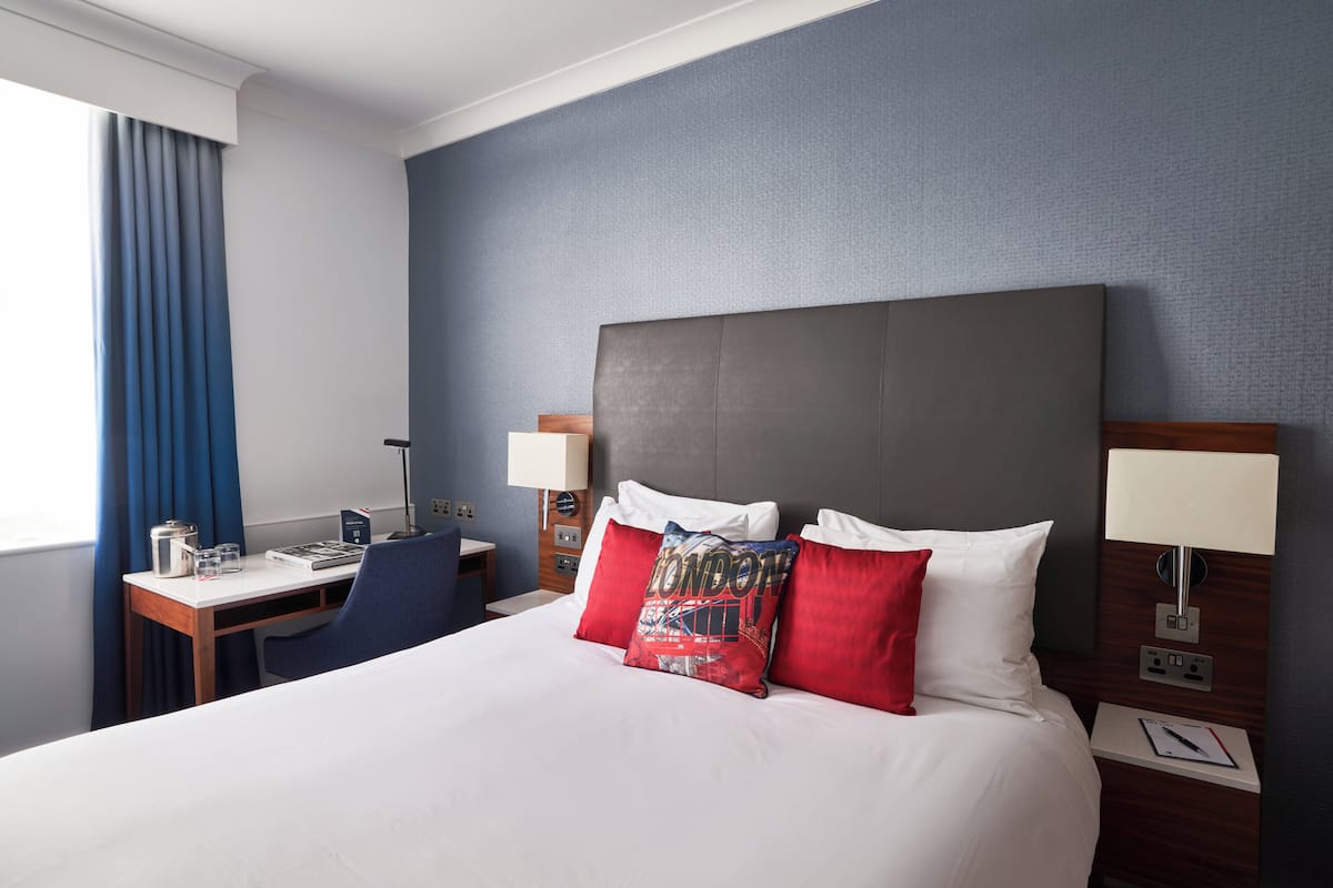 Hotellihuone, jossa on suuri sänky, työpöytä ja tuoli.