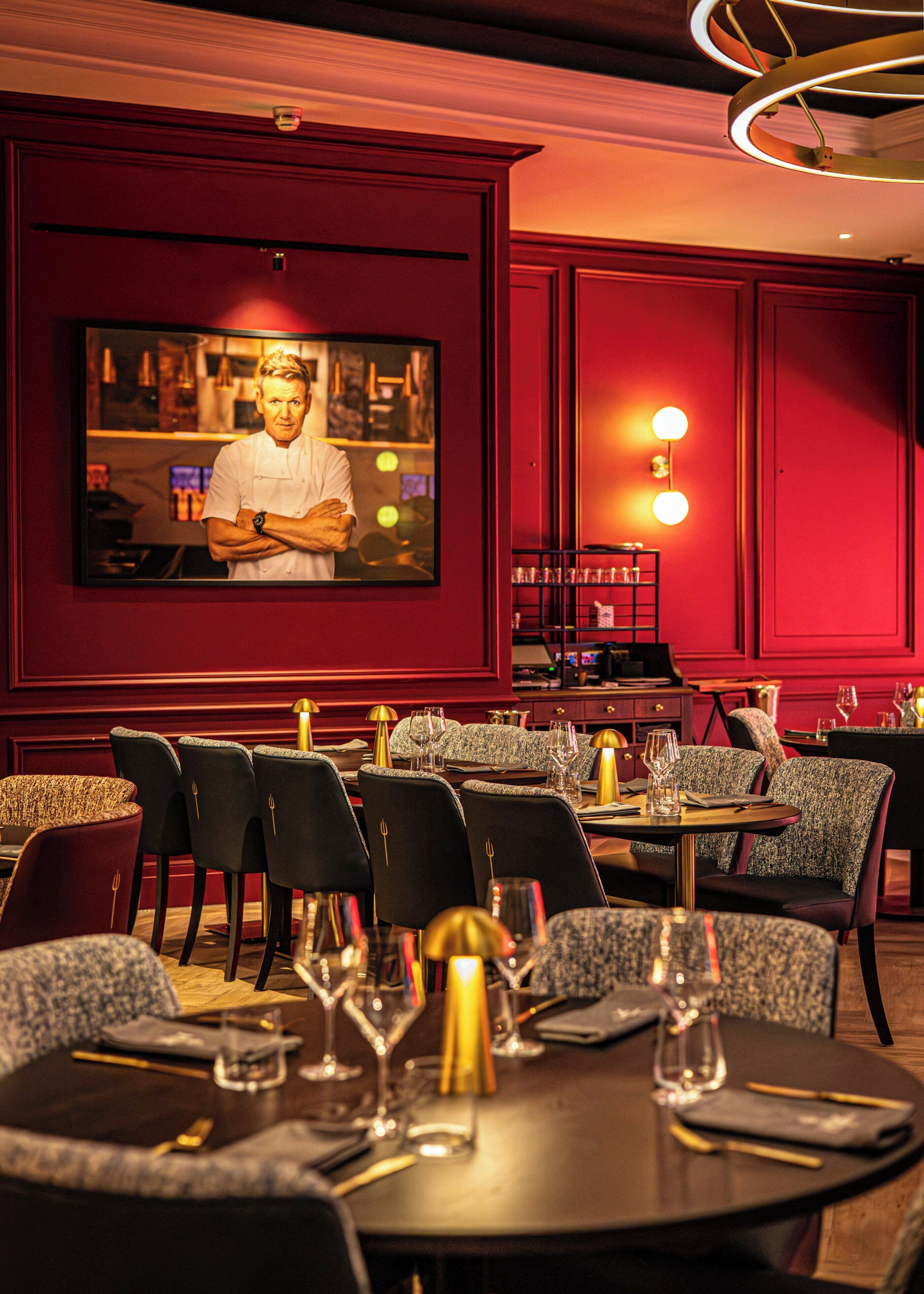 A restaurant interior with red walls, multiple dining tables, and chairs.