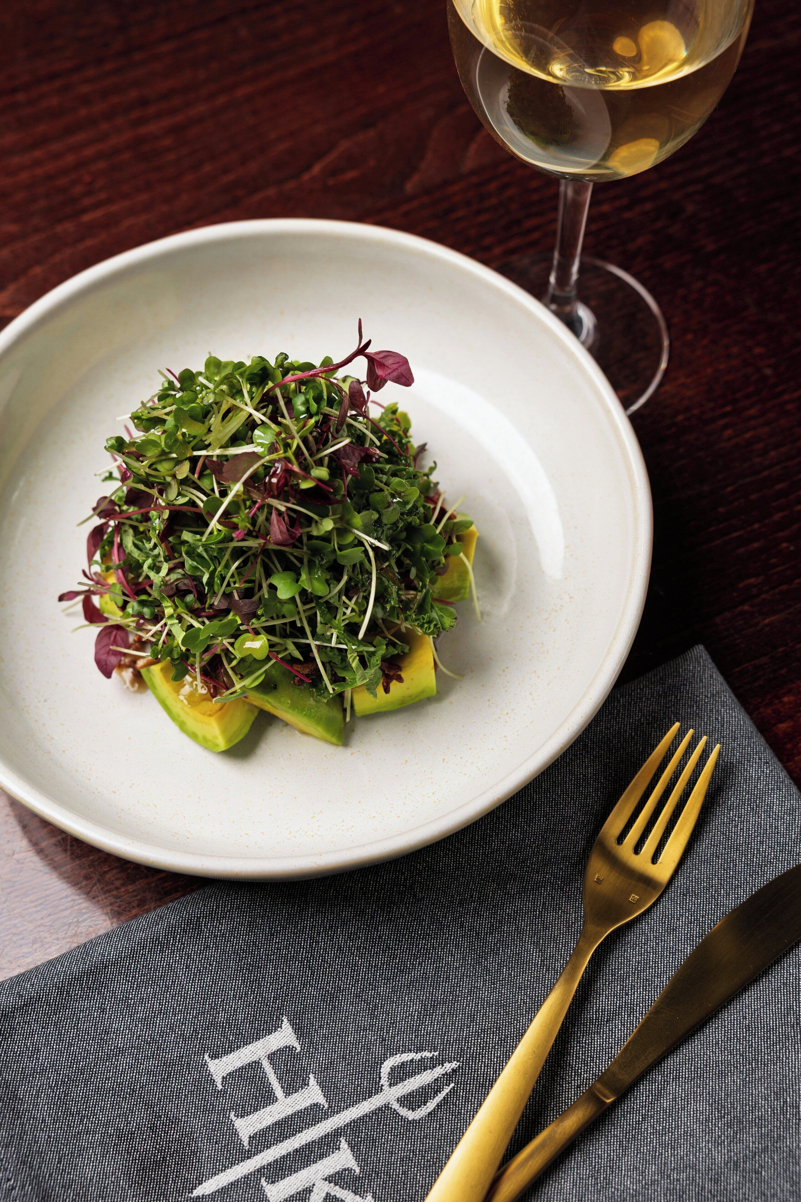 A plate of food with a glass of white wine on a table.
