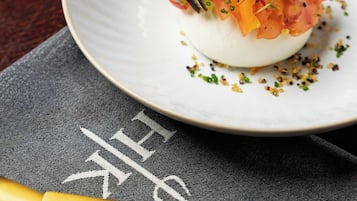 Un piatto bianco con cibo, un bicchiere di vino bianco e un tavolo in legno scuro.