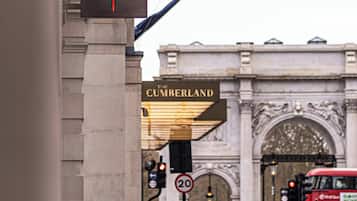 Entrada de un hotel con un cartel que dice 'The Cumberland' y una bandera de 'HIK'.