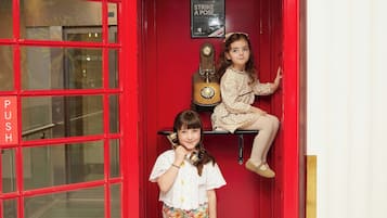 A red telephone booth with a sign reading 'TELEPHONE' and a small shelf with a guitar.