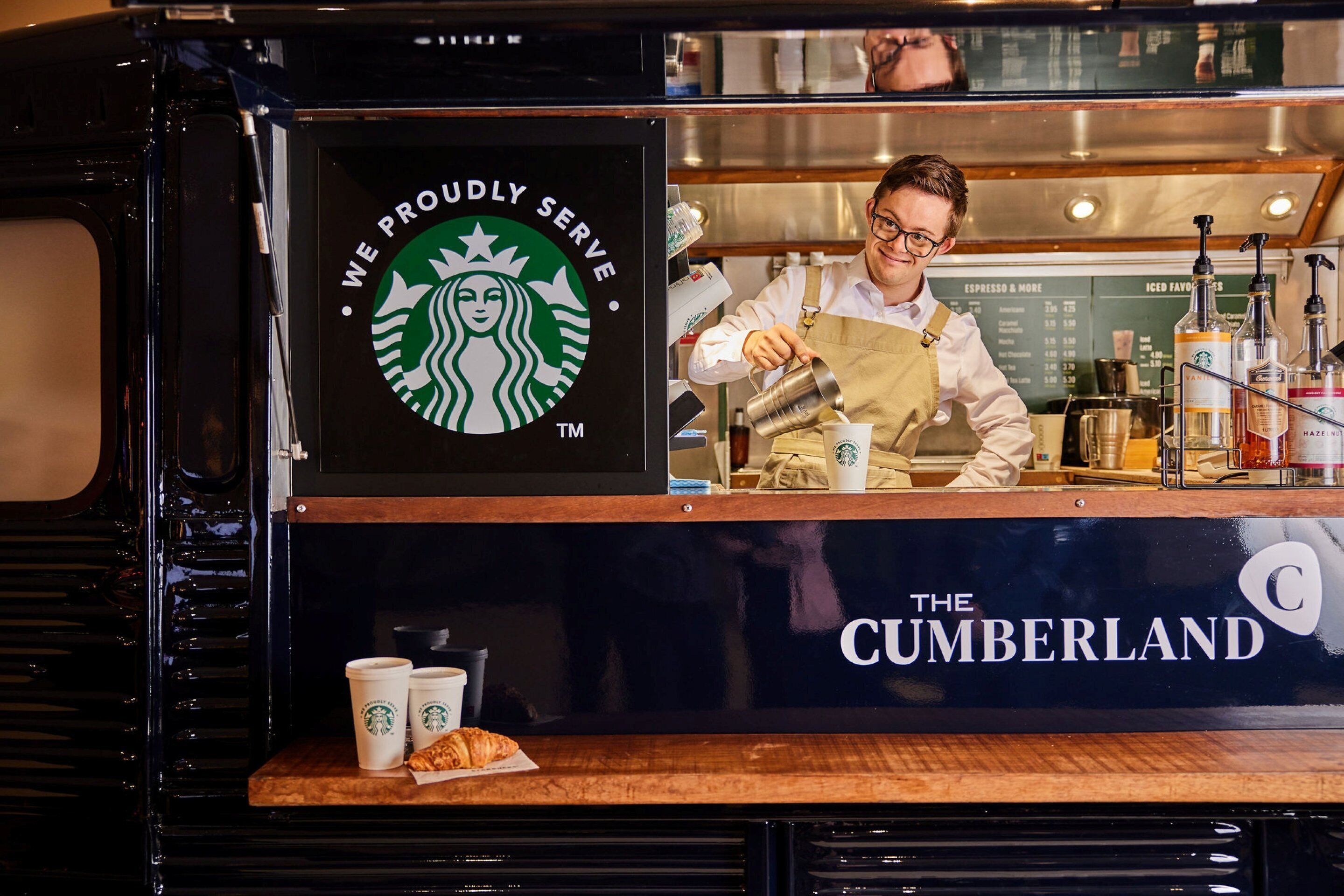 Ein Starbucks-Tresen mit einer Speisekarte und einer Person, die ein Getränk zubereitet.