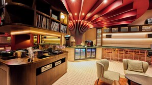 A bar area with a counter, bookshelves, and seating. - The Cumberland, London (London)