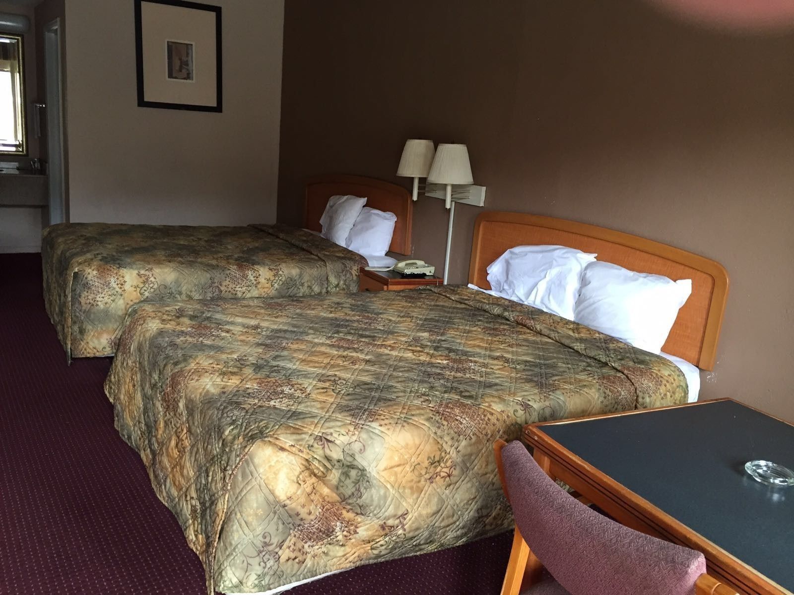Habitación de hotel con dos camas, un escritorio y una silla.
