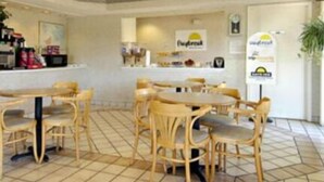 Un restaurante con mesas y sillas de madera, piso de baldosas y una barra con diversos artículos.