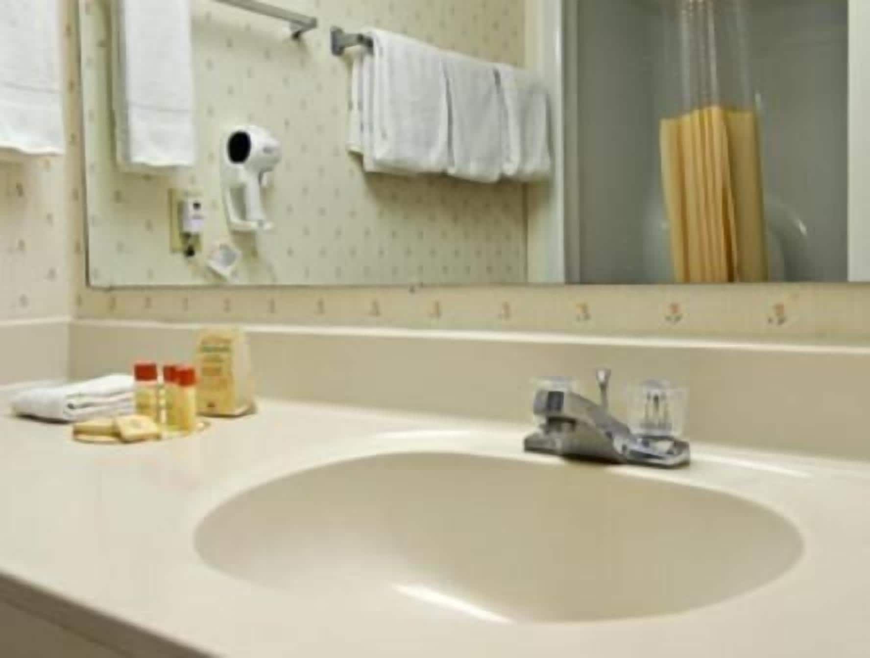 A bathroom with a sink, mirror, towel rack, and a shower.