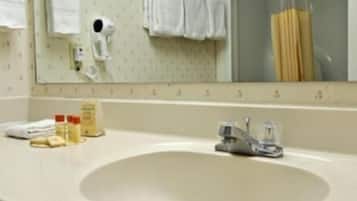 A bathroom with a sink, mirror, towel rack, and a shower.