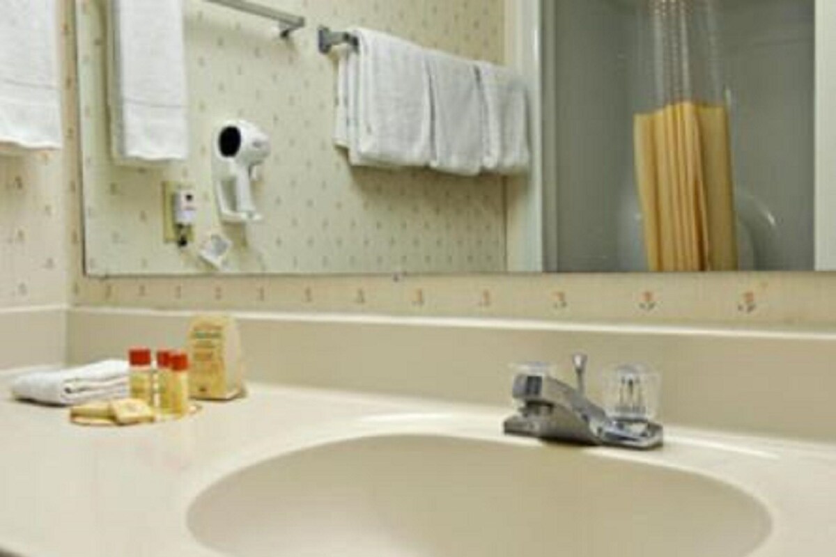 A bathroom with a sink, mirror, towel rack, and toiletries.