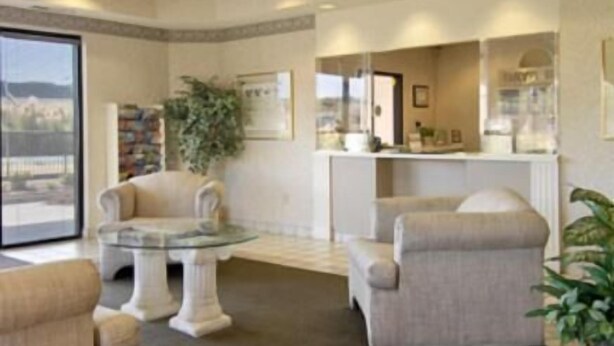 Un amplio salón con una mesa de centro de vidrio, sillones color beige y una estantería.