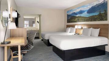 A hotel room with two beds, a desk, a chair, a large window with a mountain view, and a painting on the wall.