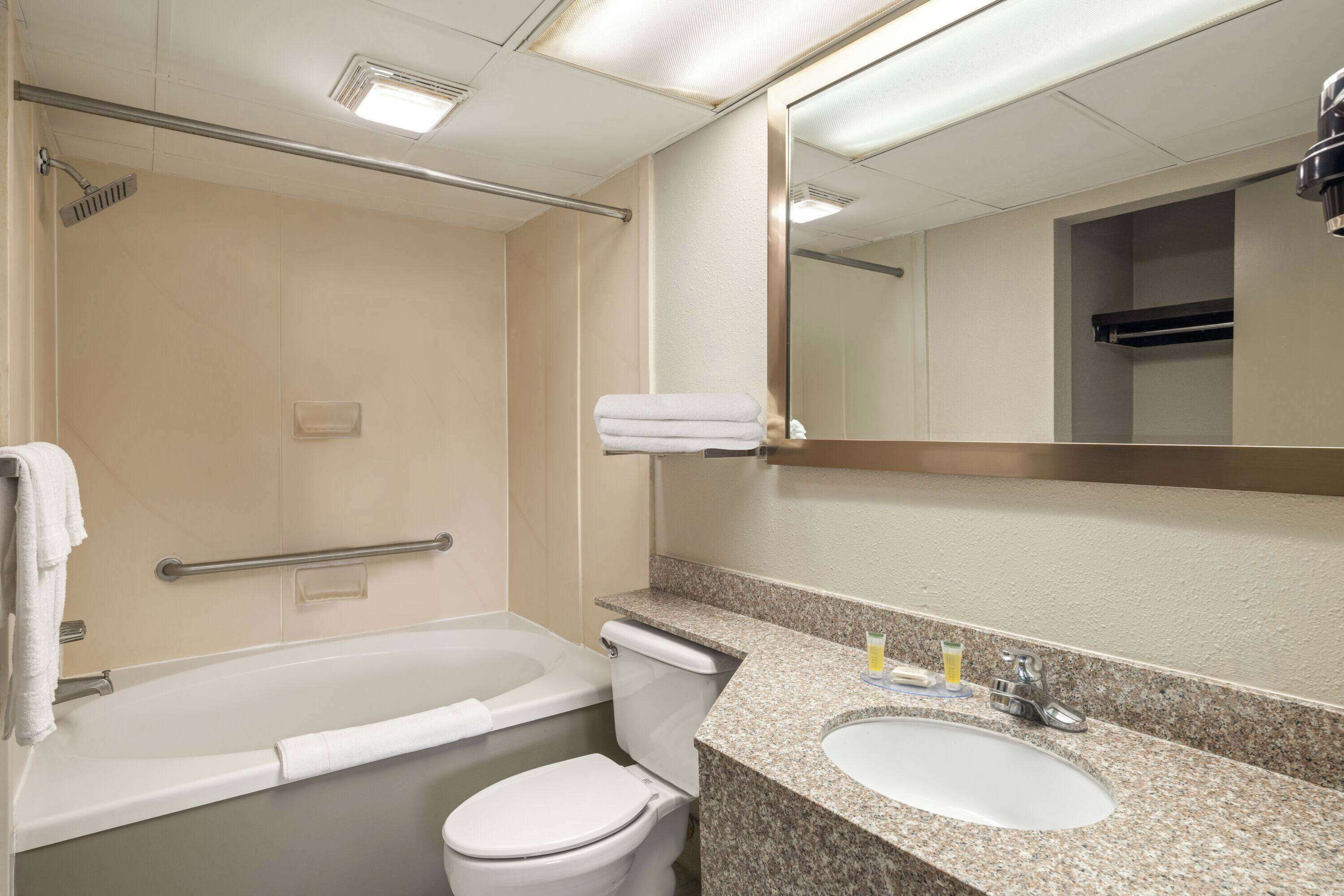 A bathroom with a bathtub, toilet, sink, and a mirror.