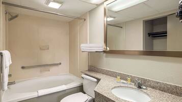 A bathroom with a bathtub, toilet, sink, and a mirror.
