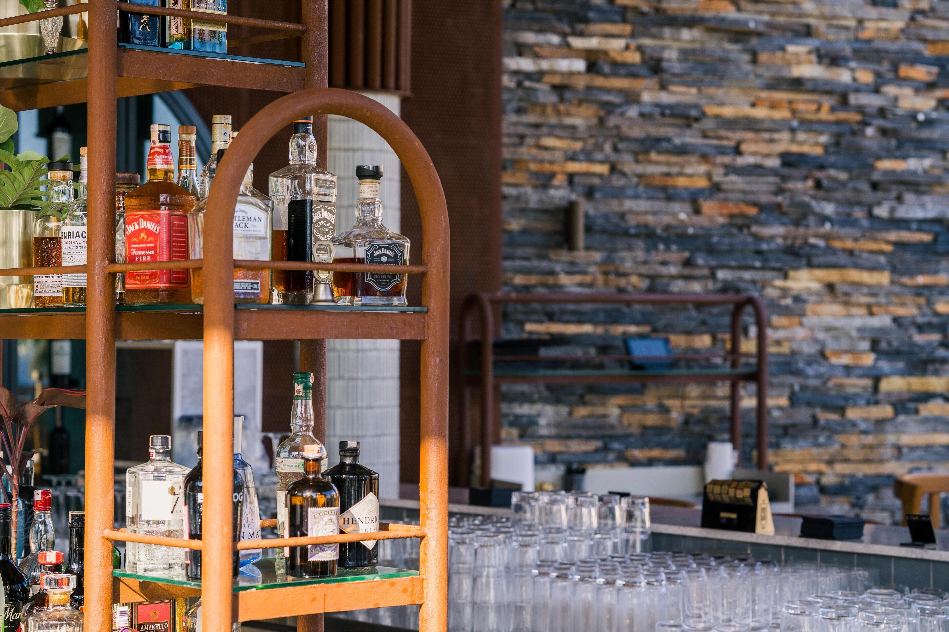 Un espace bar avec des étagères remplies de bouteilles d’alcool et de verres.