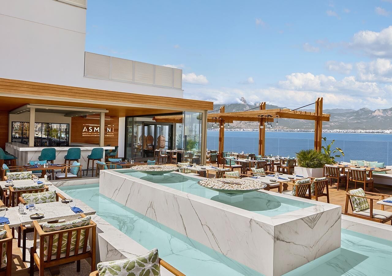 A rooftop bar with a pool, seating, and a view of the sea.