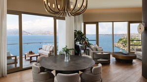 A spacious living area with a round table, comfortable seating, a large chandelier, and a view of the sea. - Akra Antalya (Antalya)