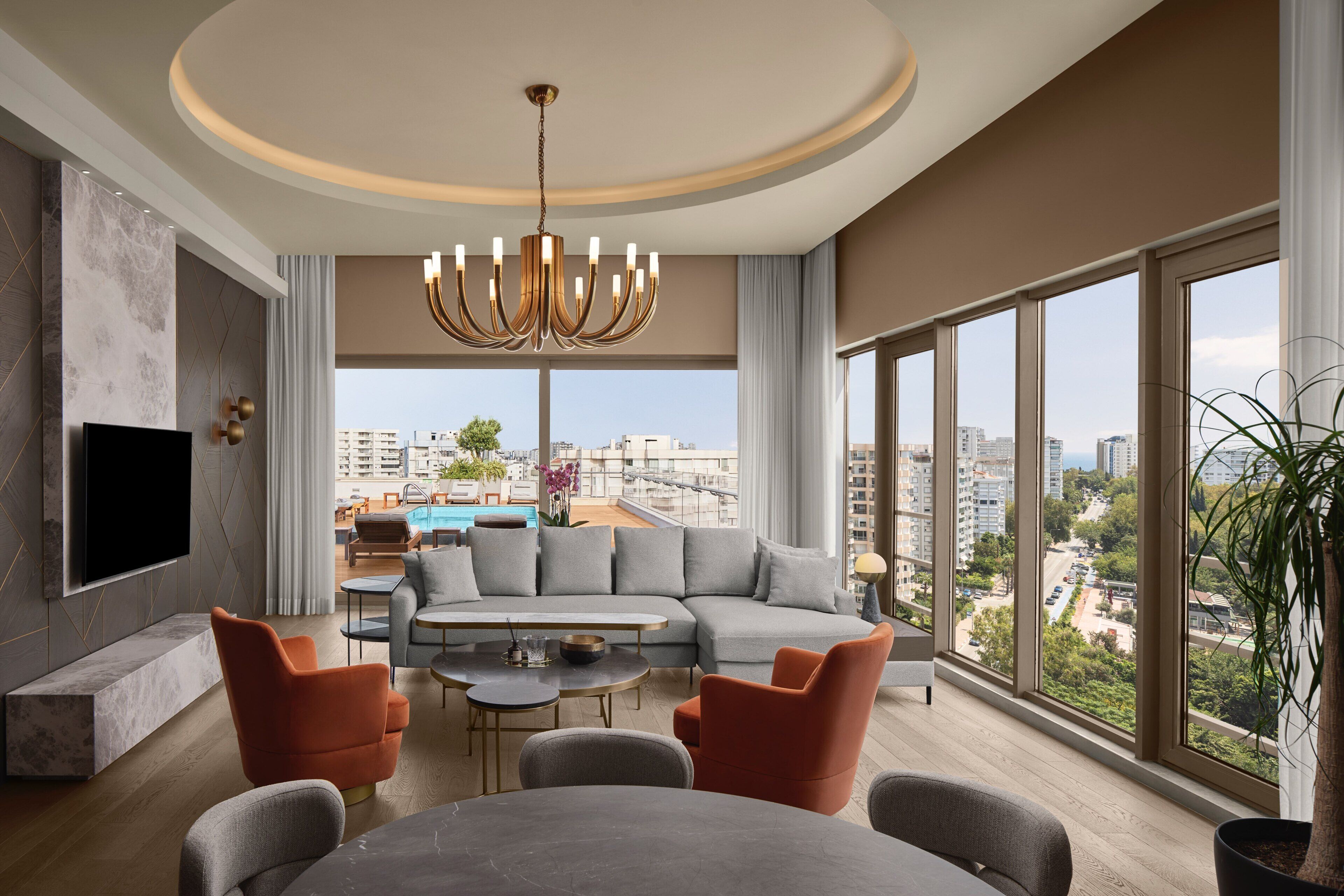 A modern living room with a large sectional sofa, a dining table, and a TV mounted on the wall.